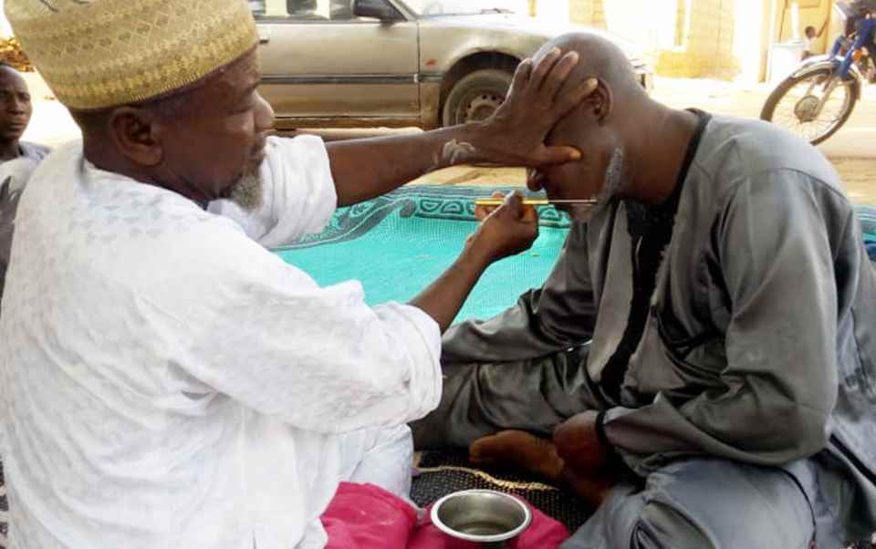Coiffeur traditionnel (wanzam) rasant un client à Bagaroua
